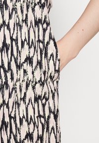 Vestido multicolorido com um padrão abstrato em preto e rosa claro. Feito de tecido leve, com uma cintura elástica e bolsos laterais.