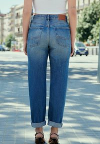 Jeans mom a vita alta di color blu chiaro, con risvolti, due tasche posteriori, etichetta in pelle sulla cintura, materiale in denim, finitura sbiadita.