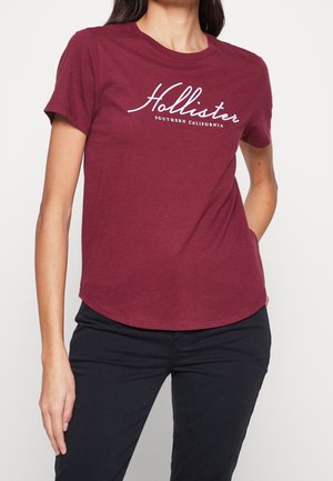 Camiseta de algodón burdeos con el logo impreso en blanco de "Hollister" y el texto "Southern California", con mangas cortas y un dobladillo redondeado.