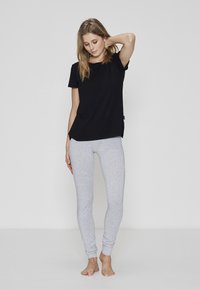 Sort kortærmet t-shirt lavet af blødt stof, parret med lysegrå strækleggings. Begge dele har et afslappet, tætsiddende design.