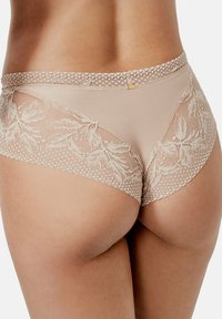 Culotte beige clair ornée d'accents en dentelle florale et d'un motif à pois, avec une base en tissu lisse et un bord en dentelle festonnée.