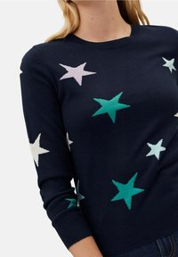 Navy blue sweater with multicolored star patterns in pink, white, and teal. Ribbed neckline and cuffs, made from a soft knit material.