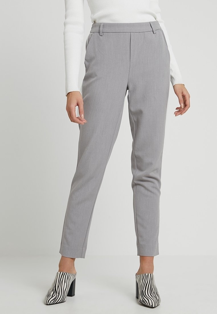 Grijze op maat gemaakte broek met een slanke pasvorm en voorplooien. G gedragen met een geribde witte top en zebra-print hakken. Platte tailleband aan de voorkant.