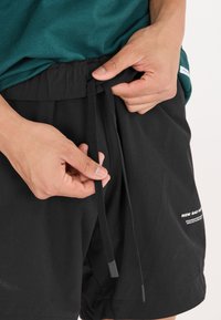 Svarta shorts med elastisk midja och dragsko. Har tryckt logotyp och ett mjukt, lätt tyg.