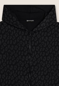 Haut à capuche zipp�é noir avec un motif léopard sombre subtil, présentant une fermeture éclair à l'avant et une capuche doublée. Texture de tissu douce.