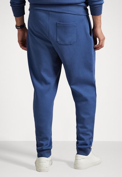 Μπλε βαμβακερές φόρμες με ευθεία γραμμή, με πίσω τσέπη και πλάγιες τσέπες, συνδυασμένες με λευκά αθλητικά παπούτσια. Μαλακή, χαλαρή υφή.