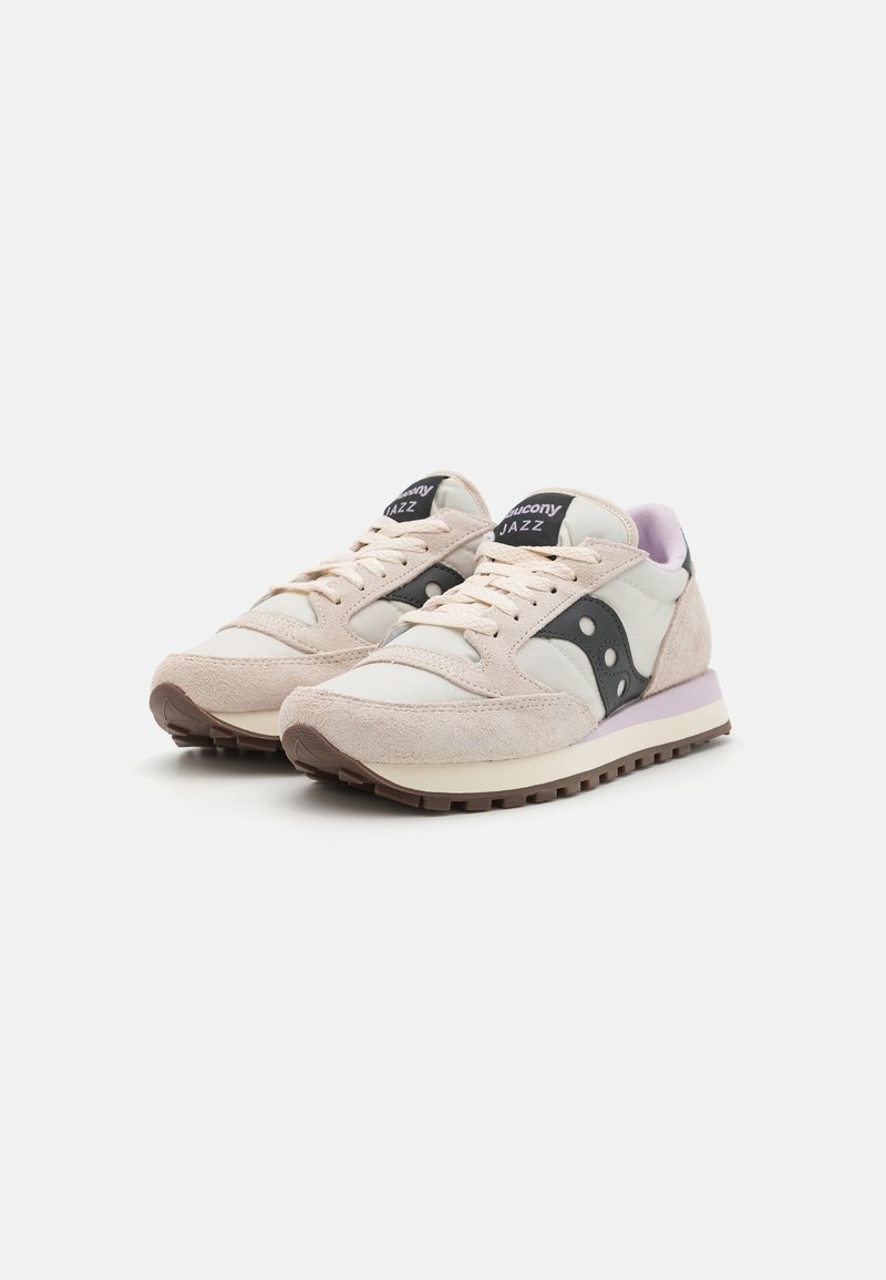 Sneaker con una combinazione di pelle e scamosciato beige chiaro, un accento triangolare nero e un tallone viola. Presenta suola in gomma marrone e chiusura con lacci.