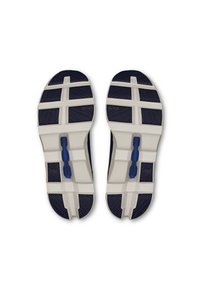 Semelles de chaussures avec un schème de couleurs bleu marine et blanc, présentant des motifs de traction texturés et un détail d'accent bleu sur le côté.