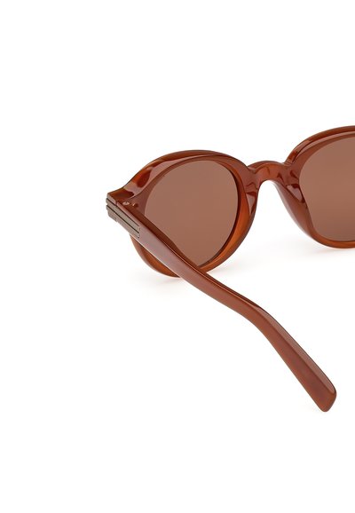 Occhiali da sole con lenti tonde di colore marrone, una montatura lucida e aste sottili. Il colore è un marrone caldo e ricco, che enfatizza una texture morbida.