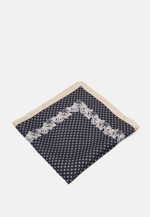 Jedwabny szal z granatowym tłem, drobnym białym wzorem kwiatowym, beżową obwódką oraz większym wzorem kwiatowym wzdłuż krawędzi.