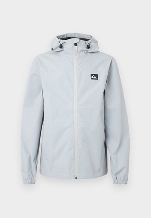 Svetlo siva hooded dežna jakna s sprednjim zadrgo, elastičnimi manšetami in črno-belim logotipom na levi strani prsnega koša.