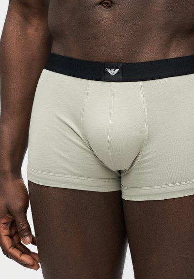 Αρσενικός κορμός με ανοιχτό γκρι μποξεράκια με μαύρη ζώνη μέσης που φέρει ένα μικρό λευκό λογότυπο Armani.