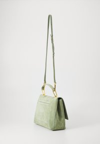 Sac à main en daim vert avec une forme structurée, accents en métal doré et une bandoulière amovible. Présente un détail de poche à l'avant.
