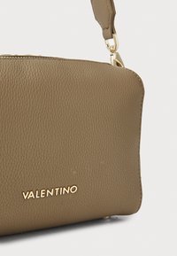 Borsa in pelle marrone testurizzata con zip, accessori in oro e il marchio "VALENTINO" impresso sul davanti.