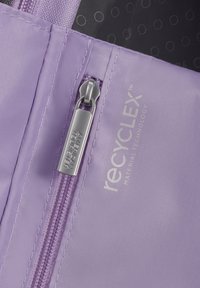 Tessuto riciclato lilla con una superficie liscia, dotato di una zip argentata e dell'etichetta "recyCLEX™ Material Technology". Interno nero con punti sottili.