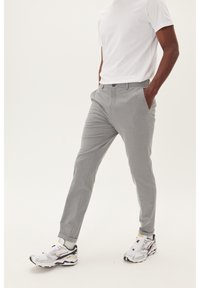 Ljust grå byxor med skräddarsydd passform, slät front, sidofickor och en mjuk textur, tillsammans med vita sneakers.