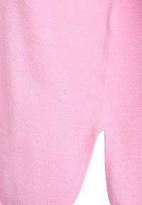 Różowy sweter wykonany z miękkiego materiału, z dekoltem w kształcie litery V u dołu. Gładka faktura z lekko elastycznym splotem.