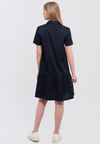Navyblauwe katoenen shirtjurk met korte mouwen, een kraag en een gerimpelde zoom. Glad textuur, iets relaxte pasvorm. Casual ontwerp met minimale details.