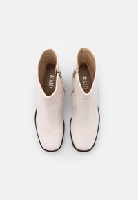 Light pink ankle boots with a smooth finish, zipper detail on the side, and a black sole. Interior shows a branded insole.