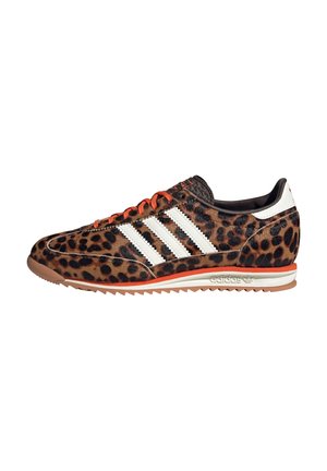 Low-profile sneaker with brown and black leopard print, white Adidas stripes, orange laces, and a gum sole with orange trim.
