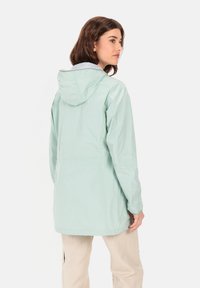 Lichtgroene regenjas met capuchon, lange mouwen en een relaxed fit. Glad textuur met een verstelbare taille en een eenvoudig design.