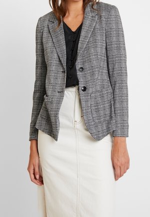 Blazer grigio a quadri in tessuto intrecciato con vestibilità su misura, rever a lancia, chiusura a due bottoni e tasche frontali, abbinato a una gonna color crema.