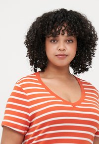 Orange cotton t-shirt with white horizontal stripes, short sleeves, and a V-neckline. Fabric appears soft with a casual fit design.
