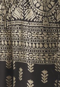 Černá tkanina s zlatými vzory, včetně květinových a geometrických designů. Stahovací pás s hladkou texturou.