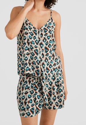 Kvinde iført ærmeløs V-hals top og matchende shorts med blå, brune og sorte abstrakte leopardpletter på hvid baggrund.