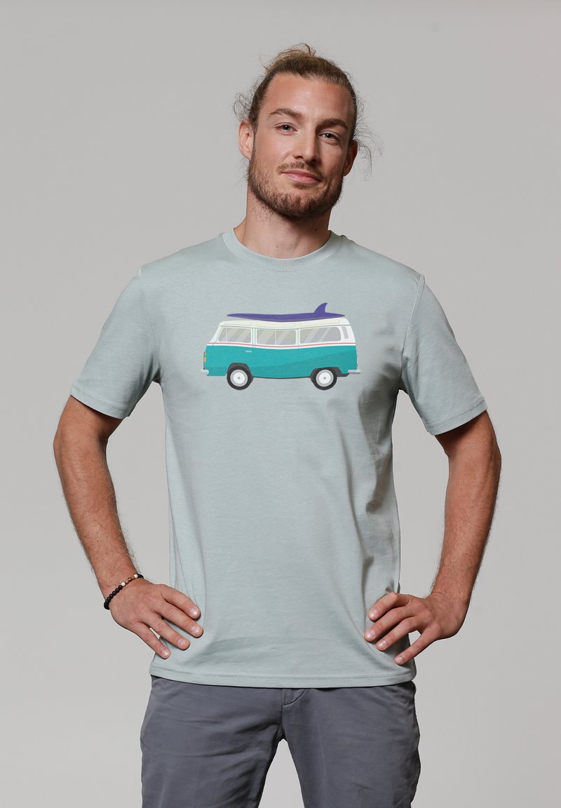 Light green t-shirt featuring a graphic of a retro van with a surfboard. Short sleeves, soft fabric, and a relaxed fit. Gray shorts worn.