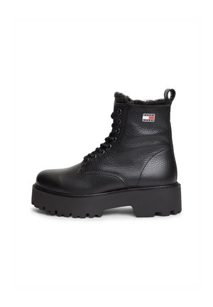 Bottine en cuir noir texturé à lacets avec semelle épaisse à rainures et petit patch logo rectangulaire sur le côté.