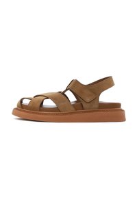 Brown suede sandals with a thick, textured rubber sole. Features crossed straps and a back strap for support. Adjustable velcro fastening.
