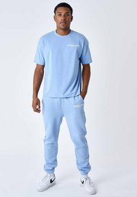Lichtblauw katoenen t-shirt en bijpassende joggingbroek, met witte tekst "PROJECT X PARIS" op de borst en dij, met elastische manchetten en tailleband.