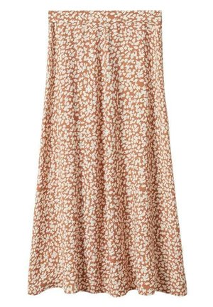 Femme portant un top blanc sans manches noué, une jupe midi orange à motifs floraux, des sabots noirs, et tenant un sac tissé blanc.