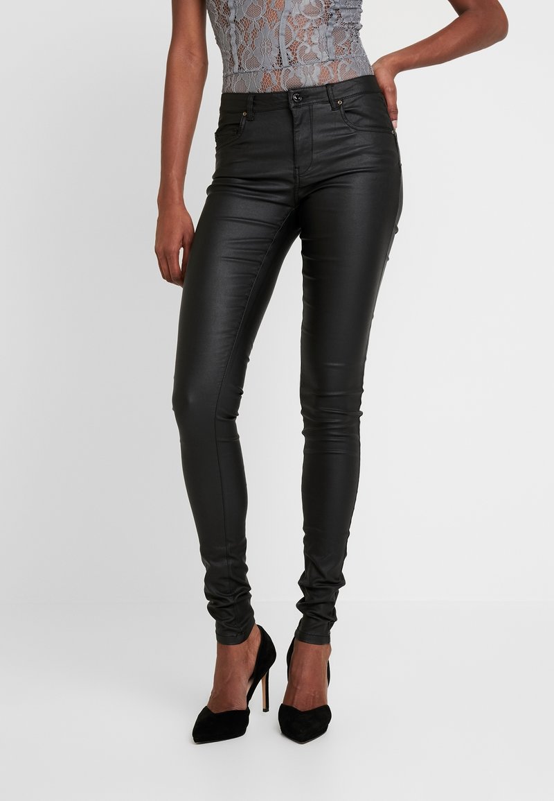 Svarta byxor i konstläder med slim fit, gylf med dragkedja och två framfickor. Bärs med svarta högklackade skor. Strukturerad yta.