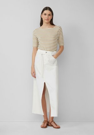 Striped beige and white short-sleeve top paired with a long white skirt featuring a front slit and tied waist, worn with brown sandals.