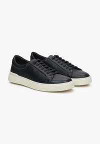 Czarne skórzane sneakersy o teksturowanym wykończeniu, z białą gumową podeszwą, sznurowanym designem i gładką osłoną palców dla dodatkowego efektu.