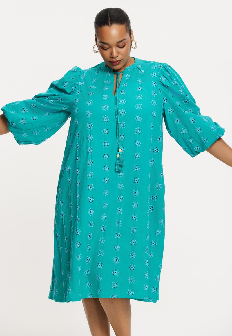 Türkises Kleid mit Puffärmeln und floralem Stickerei. Besitzt einen Ausschnitt mit Knoten- und Quasten-Detail. Lässiger, lockerer Schnitt.