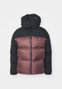 Chaqueta tipo puffer que presenta una sección superior negra y una mitad inferior color marrón burdeos, con un cuello alto, cierre de cremallera y detalle de logo en el pecho.