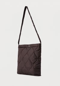 Καπιτονέ καφέ τσάντα ώμου με μακριά, λεπτή λουρί και κλείσιμο με κουμπί σνάπ. Διαθέτει μαλακή υφή και διαμαντένιο μοτίβο.