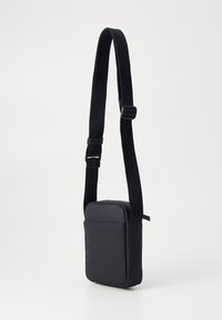Borsa a tracolla nera con forma rettangolare, realizzata in materiale liscio, dotata di una larga tracolla regolabile e di un design minimalista.