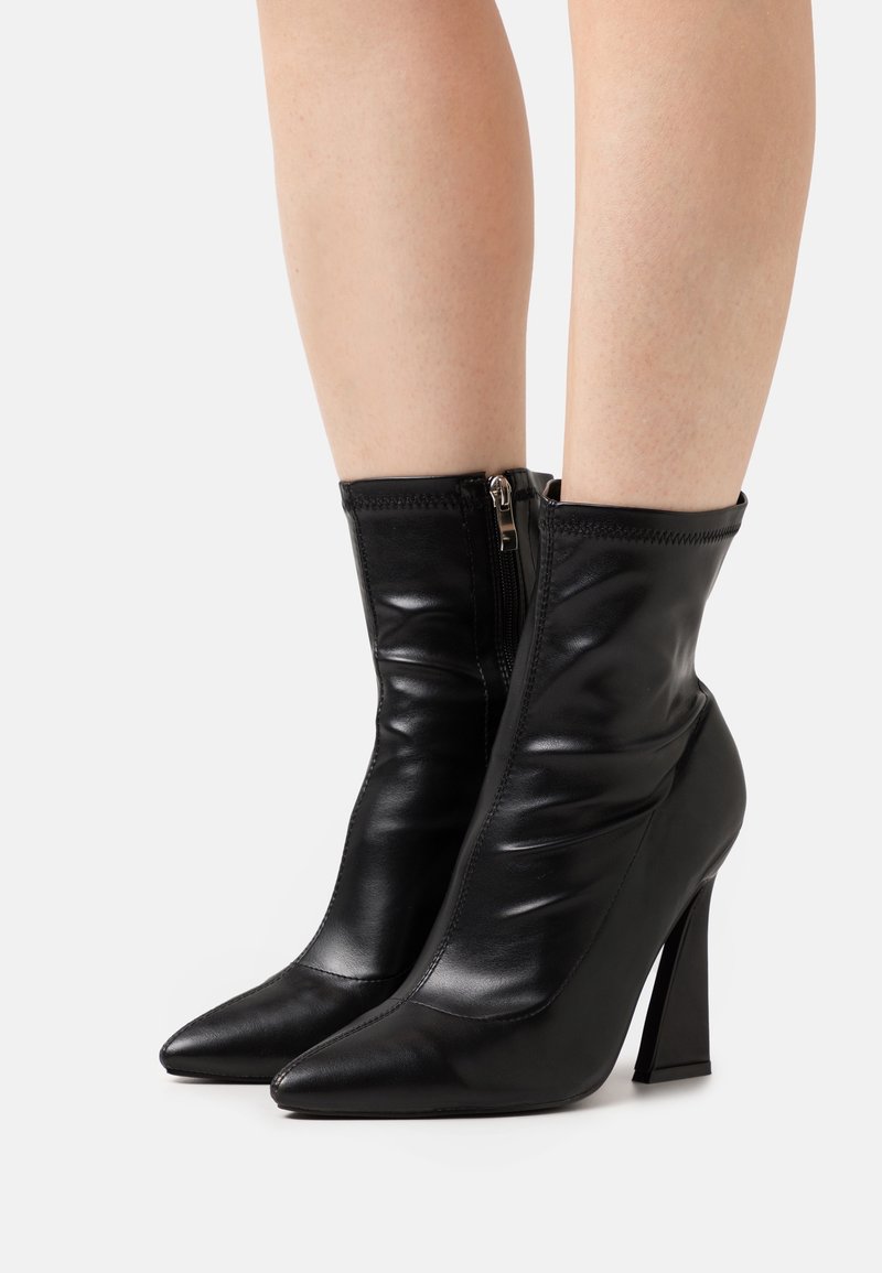 Bottes chevilles en cuir noir au design ample, bouts pointus et hauts talons carrés. Elles disposent d'une fermeture éclair latérale.