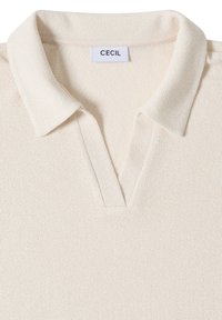 Polo en maille blanc cassé avec col court et ouverture en V, avec une étiquette de marque « CECIL » à l'intérieur de l'encolure.