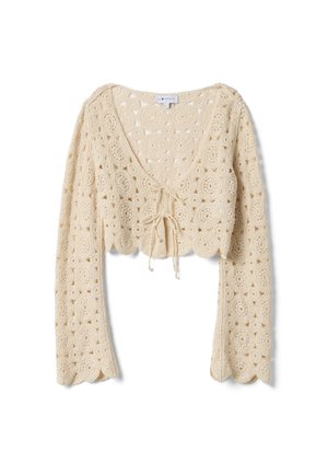 Beige gehaakt gebreid cropped vest met lange mouwen, getande randen en een striksluiting aan de voorkant.