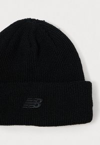 Must värvitud beanie, millel on volditud serv, tekstuuriga muster ja diskreetne must logo esiosas. Pehme, veniv materjal.