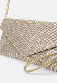 Pochette de soirée ton or recouverte de petits strass, avec une bride de poignet assortie et une poignée courte en chaîne.