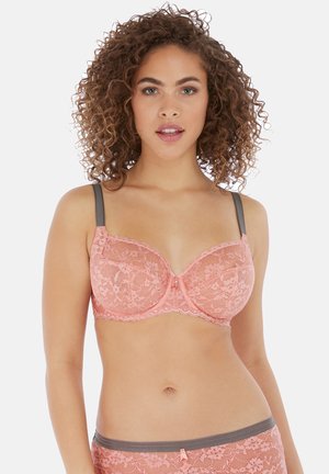 Soutien-gorge en dentelle rose doux avec des bretelles grises. Présente un motif floral et un délicat ourlet le long des bords. Détail de nœud au centre pour une touche d'accent.