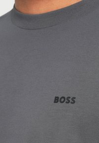 Γκρι βαμβακερό T-shirt με στρογγυλή λαιμόκοψη. Διαθέτει υφασμένο, μαύρο λογότυπο "BOSS" στο στήθος. Λεία υφή και εφαρμοστό σχέδιο.