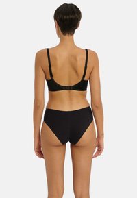 Ensemble de lingerie noire comprenant un soutien-gorge lisse et extensible avec des bretelles réglables et une fermeture à crochets, associé à des culottes noires taille haute et sans coutures.