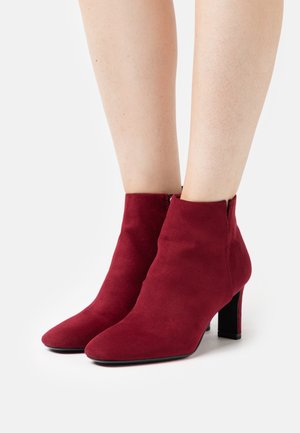 Bottines en daim bordeaux avec un bout pointu et un talon bloc. Texture lisse avec un design sans couture et une fermeture à glissière sur le côté.